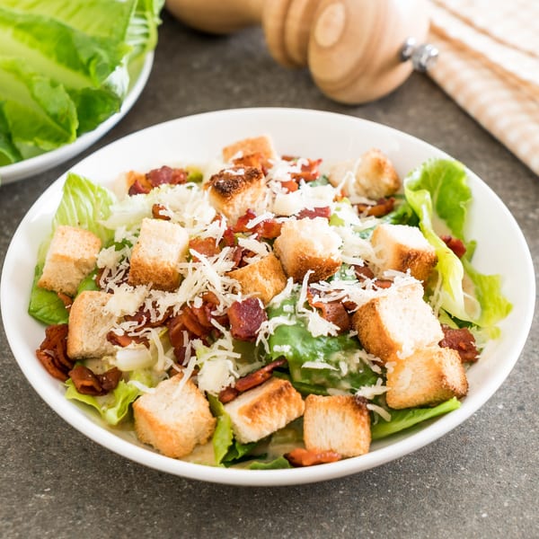 A Caesar salad from Sarah's on Park, with crisp romaine, croutons, bacon, and shredded Parmesan cheese.