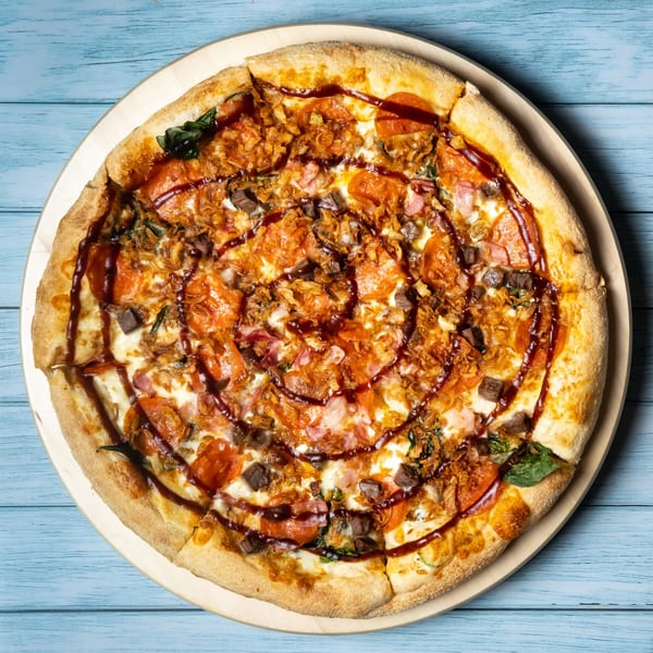 Overhead view of a Sarah's on Park pizza with pepperoni, beef, ham, spinach, and fried onions.