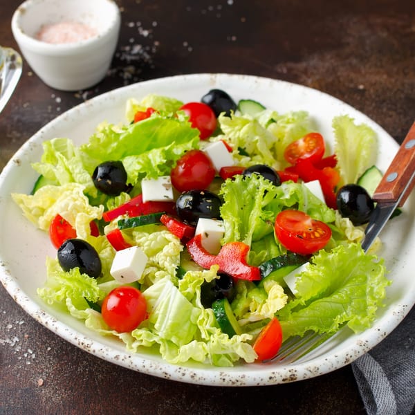 Fresh Italian salad with lettuce, tomatoes, olives, cucumbers, red peppers, and feta cheese.
